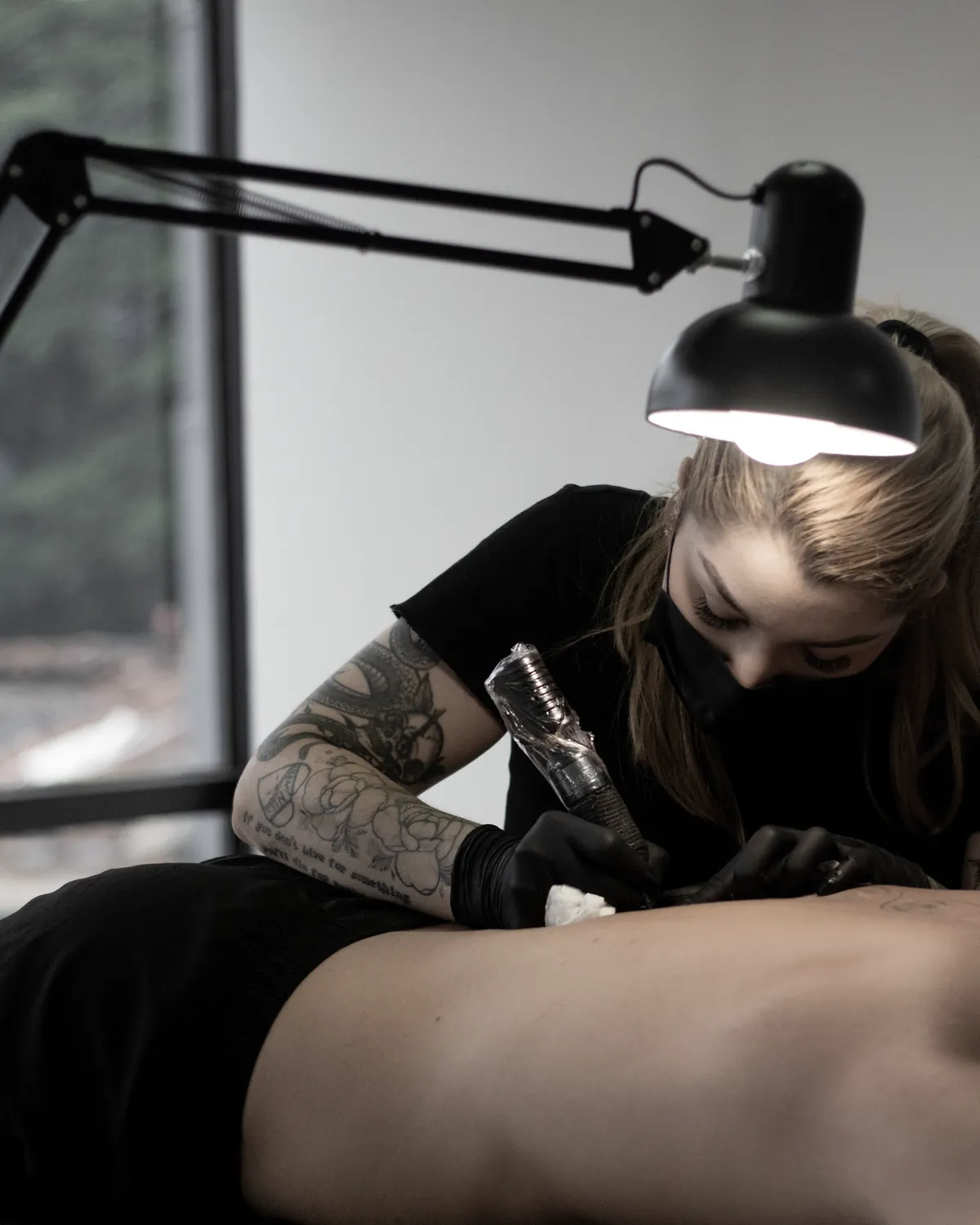 Maff Leal tatuando bajo la lámpara del estudio